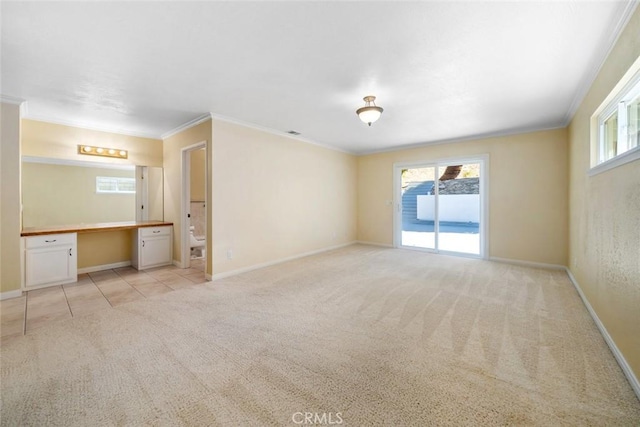 carpeted empty room featuring built in desk and ornamental molding