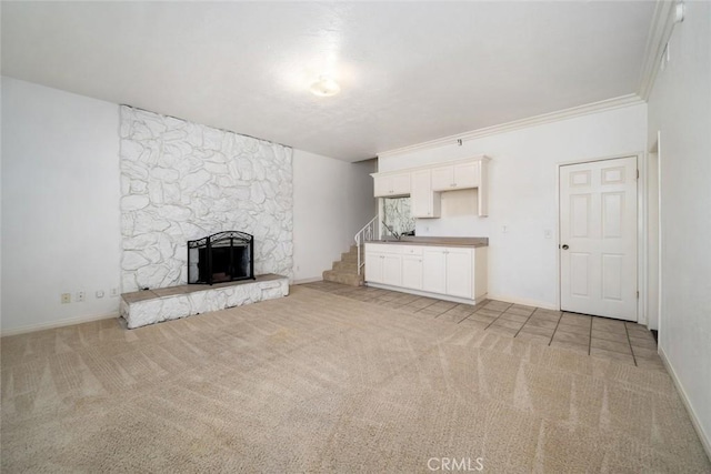 unfurnished living room with crown molding, a fireplace, and light carpet