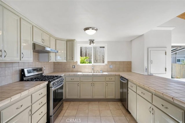 kitchen featuring sink, tile counters, plenty of natural light, and appliances with stainless steel finishes