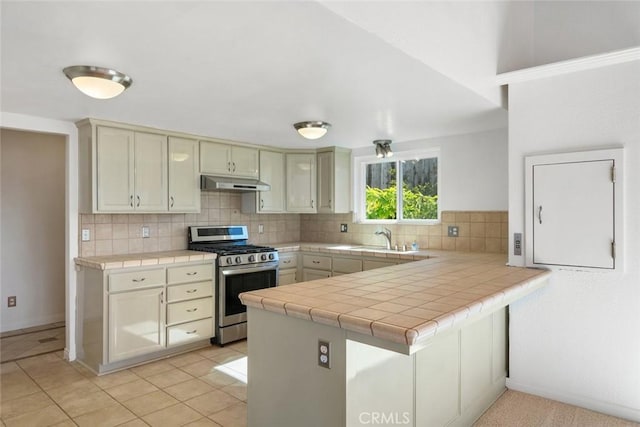 kitchen featuring tile counters, tasteful backsplash, kitchen peninsula, and stainless steel range with gas stovetop