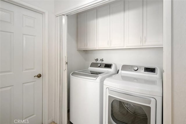 laundry room featuring separate washer and dryer and cabinets