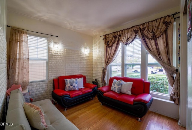 living area with hardwood / wood-style floors and brick wall