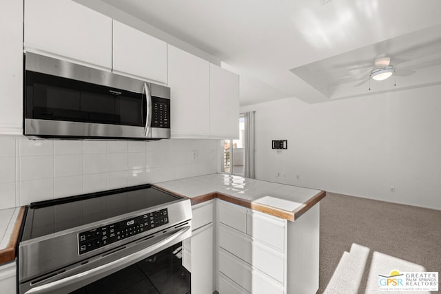 kitchen with light colored carpet, white cabinets, range, and tile counters