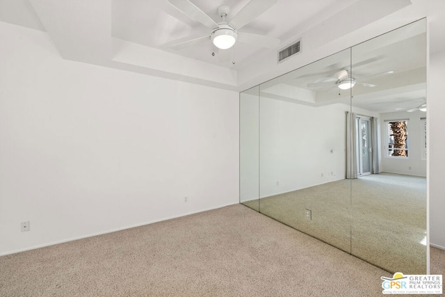 unfurnished room with ceiling fan, carpet, and a tray ceiling