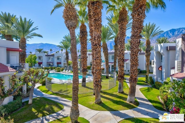 view of home's community with a lawn, a mountain view, and a swimming pool