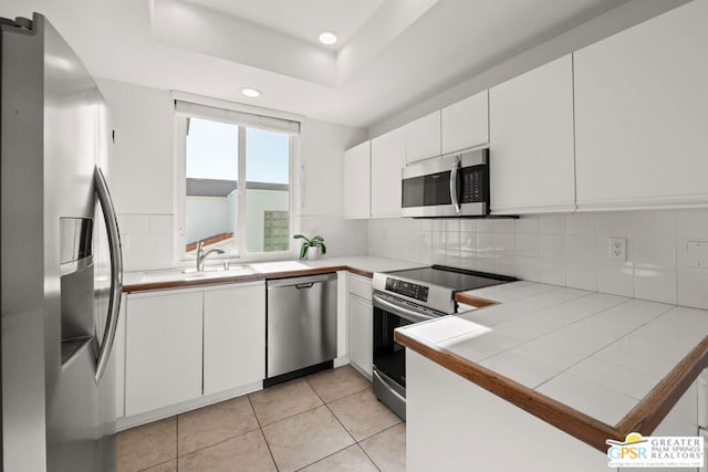 kitchen with tile countertops, appliances with stainless steel finishes, tasteful backsplash, white cabinets, and sink