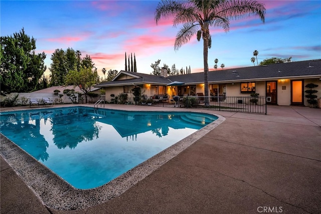 pool at dusk featuring a patio area