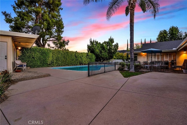 pool at dusk with a patio area