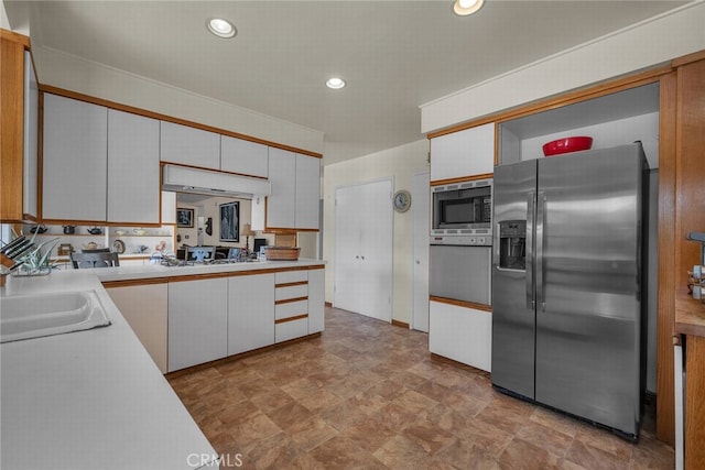 4614 La Subida Pl, Tarzana, CA 91356 - kitchen with appliances with stainless steel finishes, under cabinet range hood, light countertops, stone finish flooring, and white cabinetry