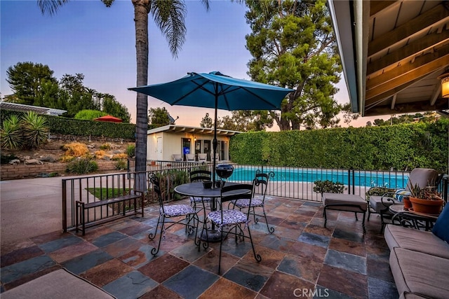 patio terrace at dusk with a fenced in pool