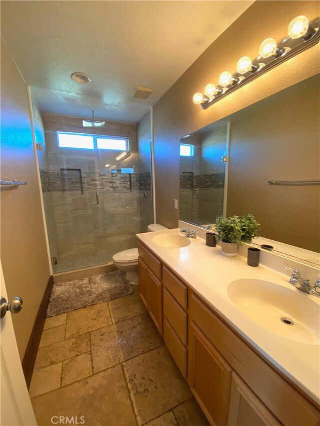 bathroom with a shower with door, vanity, and toilet