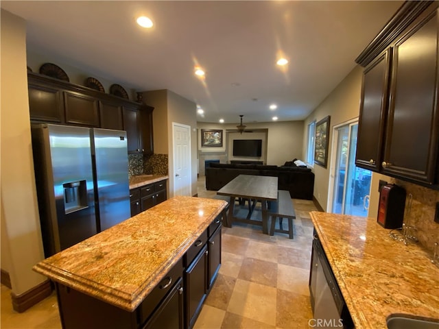 kitchen with a kitchen island, backsplash, dark brown cabinetry, appliances with stainless steel finishes, and ceiling fan