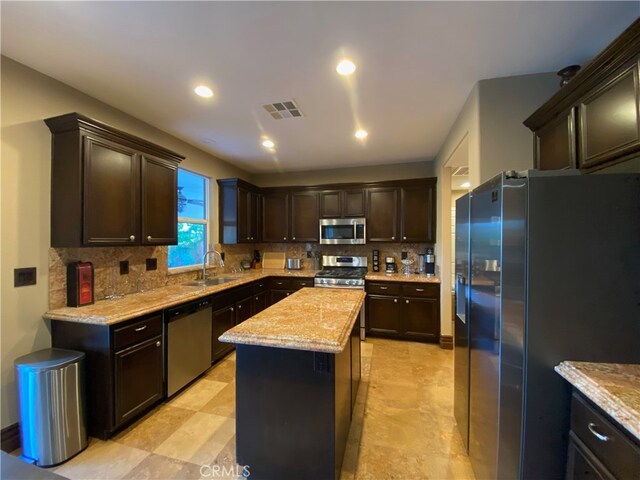 kitchen with a kitchen island, backsplash, sink, dark brown cabinetry, and appliances with stainless steel finishes