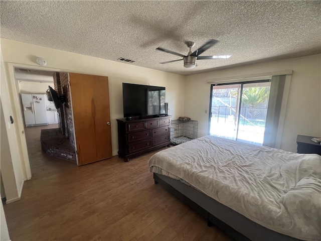 bedroom with ceiling fan, a textured ceiling, access to exterior, hardwood / wood-style flooring, and white refrigerator with ice dispenser