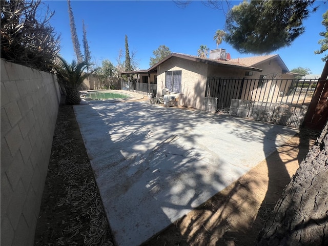 view of side of home featuring a patio and a fenced in pool