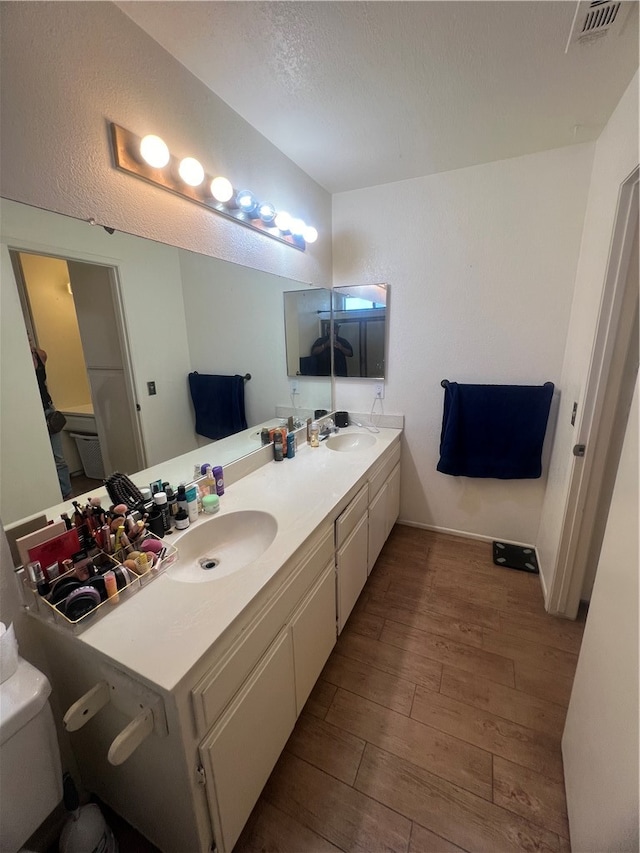 bathroom featuring vanity, toilet, wood-type flooring, and a textured ceiling