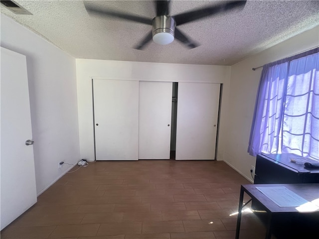 unfurnished bedroom featuring dark hardwood / wood-style floors, a textured ceiling, a closet, and ceiling fan