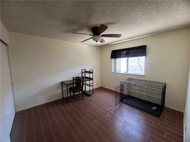 bedroom with dark wood-type flooring, ceiling fan, and a textured ceiling