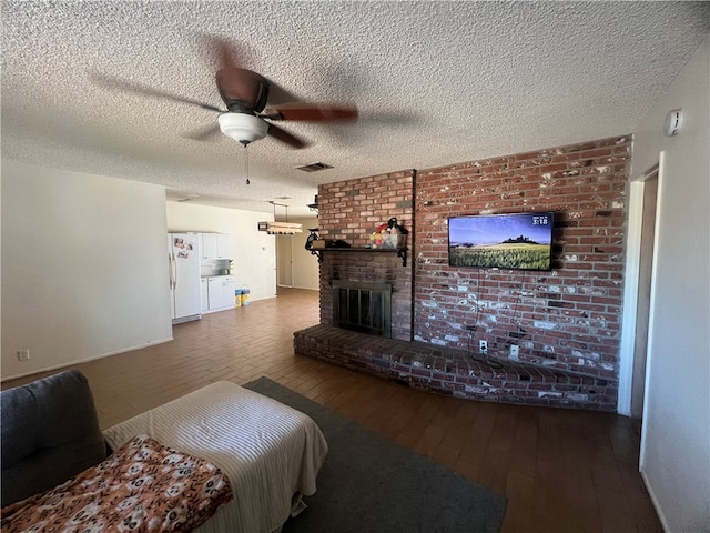 living room featuring a textured ceiling, hardwood / wood-style flooring, ceiling fan, and a brick fireplace