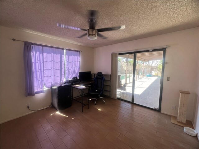 unfurnished office with ceiling fan, wood-type flooring, and a textured ceiling