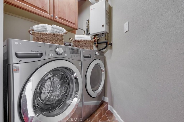 laundry room with cabinets, dark tile patterned floors, independent washer and dryer, and water heater