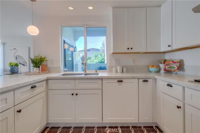 kitchen featuring decorative light fixtures, white cabinets, sink, and light stone counters