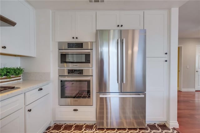 kitchen with hardwood / wood-style flooring, stainless steel appliances, white cabinets, and light stone countertops