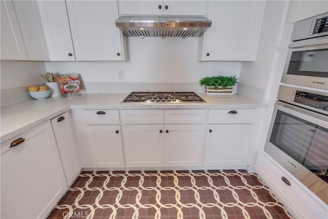 kitchen featuring light stone countertops, white cabinets, ventilation hood, and stainless steel gas stovetop