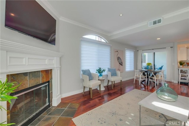 living room with a tiled fireplace, dark hardwood / wood-style floors, and ornamental molding