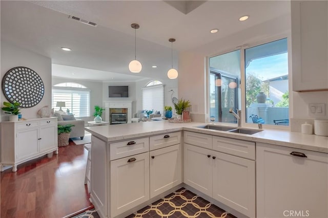 kitchen featuring kitchen peninsula, decorative light fixtures, white cabinets, and sink