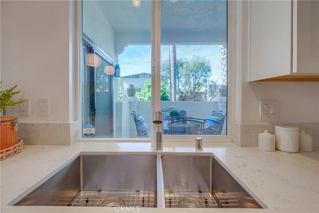 kitchen featuring white cabinets, light stone countertops, and sink