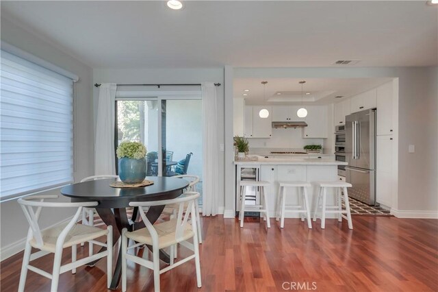 dining space with a raised ceiling and dark wood-type flooring