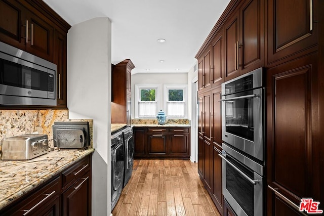 kitchen featuring tasteful backsplash, light stone counters, separate washer and dryer, light hardwood / wood-style flooring, and stainless steel appliances