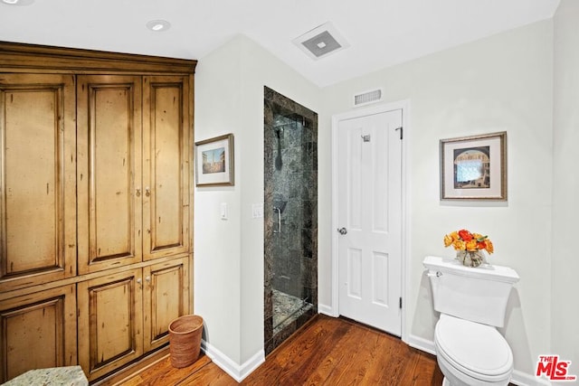 bathroom with wood-type flooring, a shower with shower door, and toilet