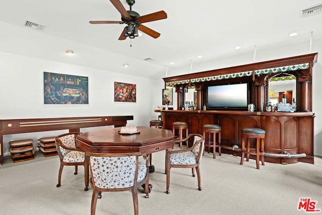 dining space featuring vaulted ceiling, indoor bar, light colored carpet, and ceiling fan