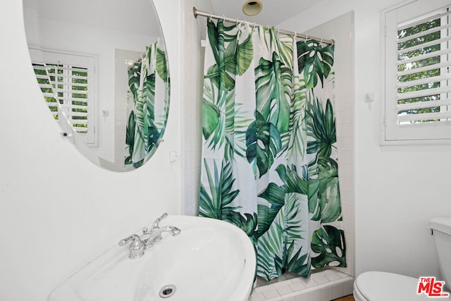 bathroom with toilet, a shower with shower curtain, and a wealth of natural light