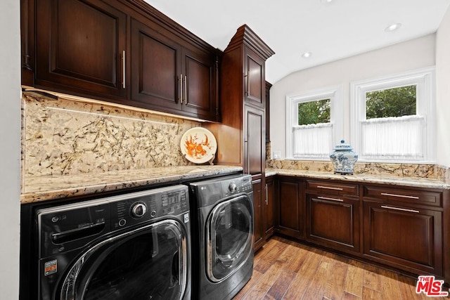 clothes washing area with cabinets, separate washer and dryer, and light hardwood / wood-style flooring