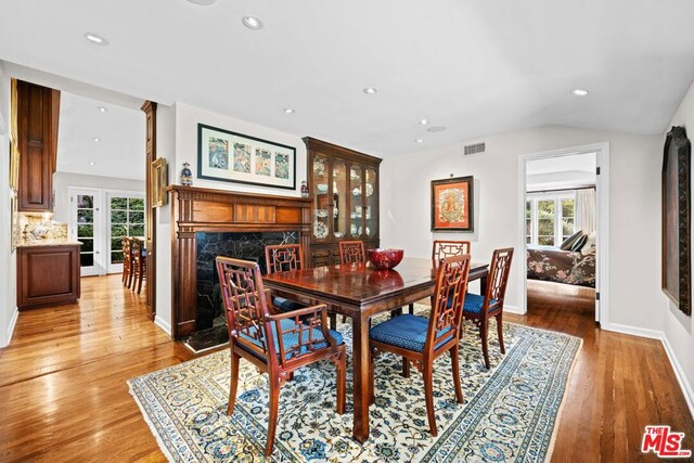 dining room with vaulted ceiling, a high end fireplace, and hardwood / wood-style floors