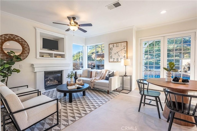 living room featuring ceiling fan, crown molding, and a wealth of natural light