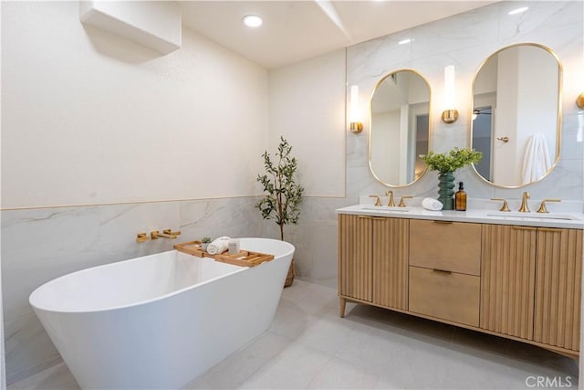 bathroom with tile patterned flooring, a washtub, tile walls, and vanity