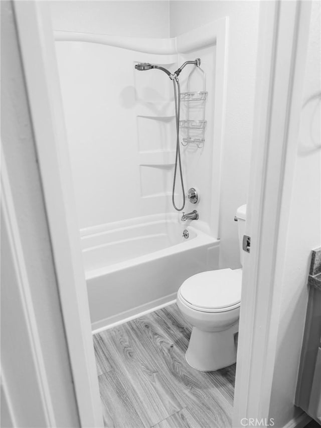 bathroom featuring toilet, washtub / shower combination, and hardwood / wood-style flooring