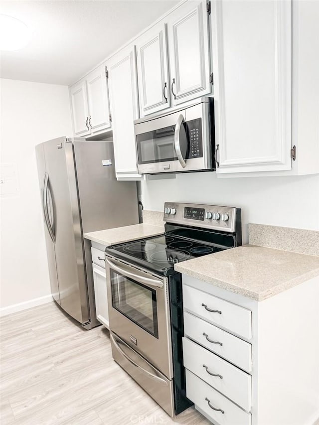 kitchen with white cabinets, light wood-type flooring, and stainless steel appliances