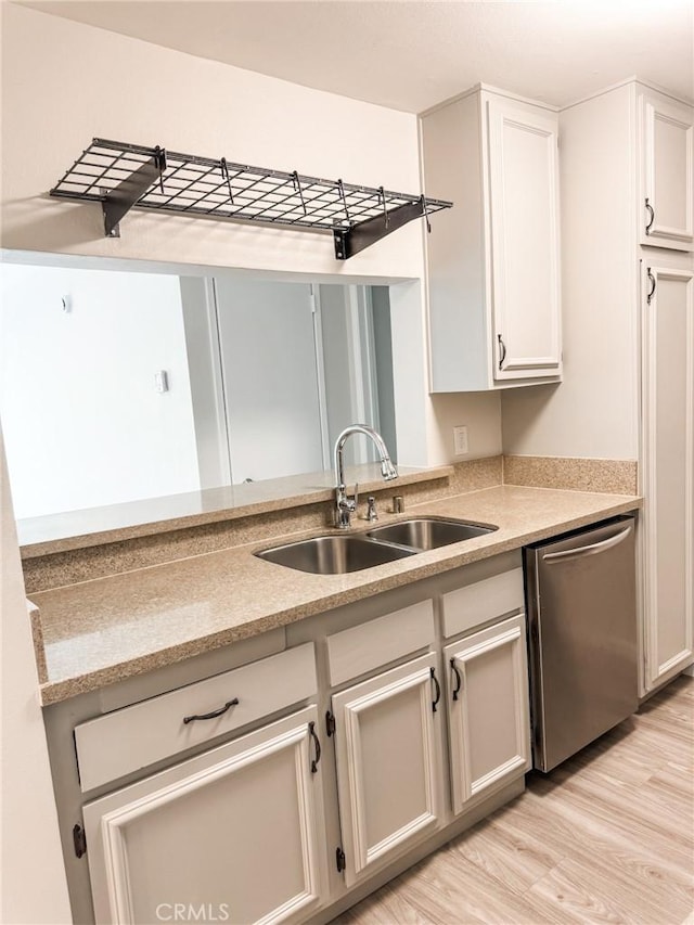 kitchen featuring white cabinetry, sink, stainless steel dishwasher, and light hardwood / wood-style flooring