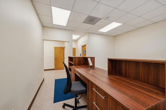 carpeted office space featuring built in desk and a drop ceiling