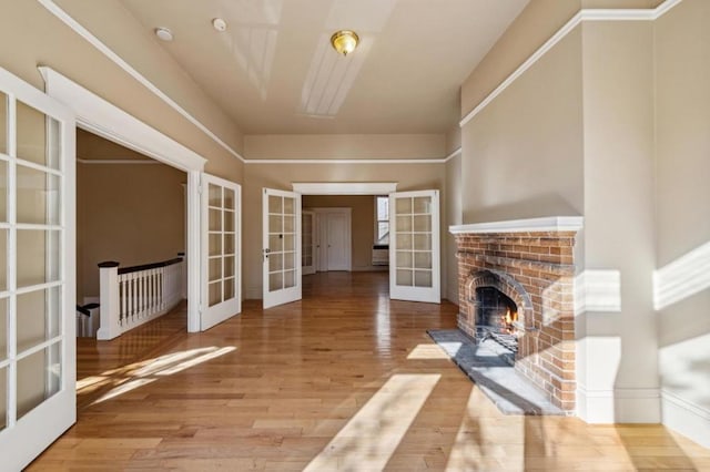 unfurnished living room with wood-type flooring, a fireplace, and french doors