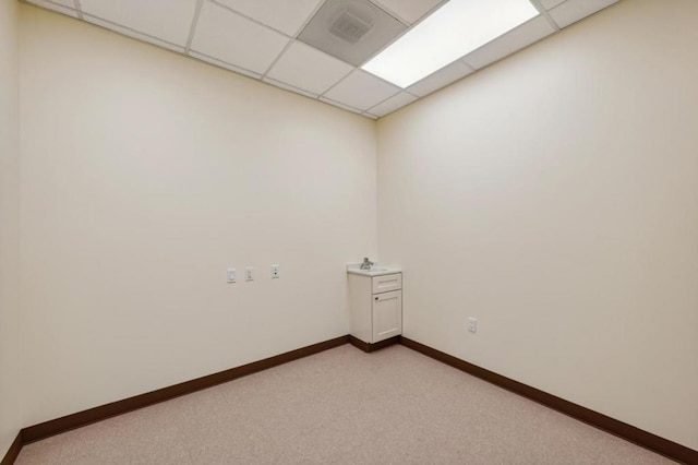 unfurnished room featuring light carpet, a drop ceiling, and sink