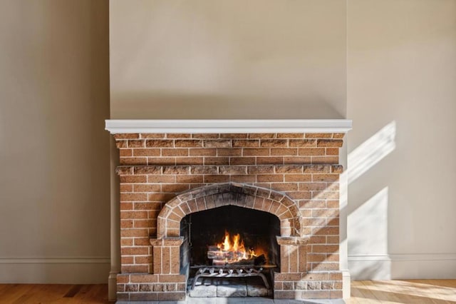 interior details with wood-type flooring and a brick fireplace