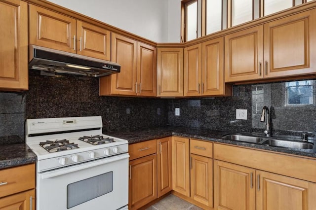 kitchen with sink, dark stone countertops, gas range gas stove, and tasteful backsplash