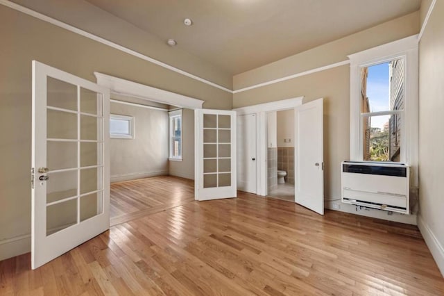 unfurnished room featuring heating unit, french doors, and light wood-type flooring