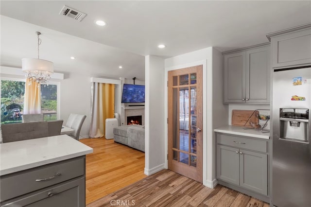 kitchen with stainless steel fridge, gray cabinets, light wood-style floors, and visible vents